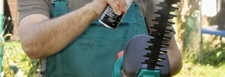 Person ölt eine Heckenschere